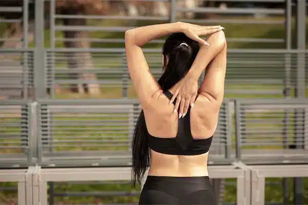 Photo of a woman in workout clothing stretching her back before she exercises